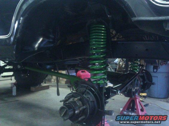 Underside of a vehicle showing suspension work with bright green coil springs and brake components