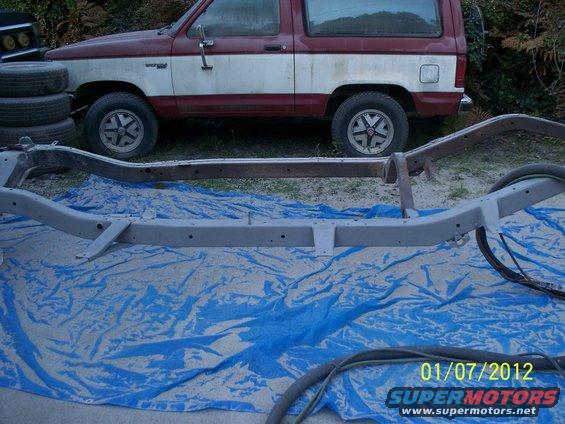 1990 Ford Bronco parked behind its chassis on a blue tarp