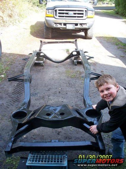 Chassis frame with a boy and a Ford truck in the background