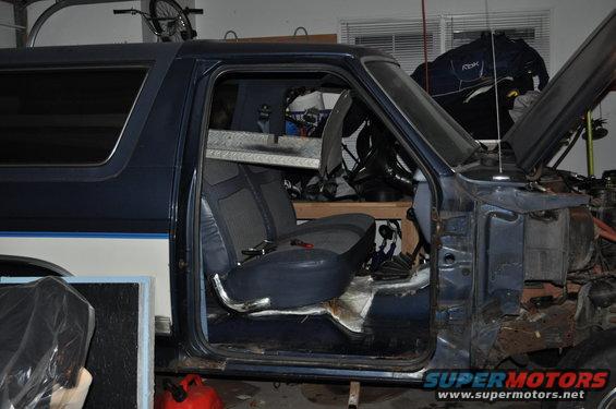 Blue SUV with open doors, showing interior and partially disassembled engine bay. A bicycle is mounted overhead