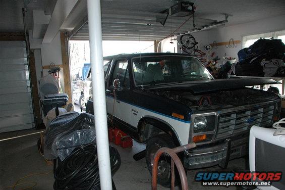 Dark blue and white Ford Bronco with hood open, parked in a garage