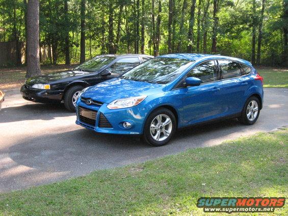 Blue 2012 Ford Focus hatchback parked on asphalt driveway, front 3/4 view