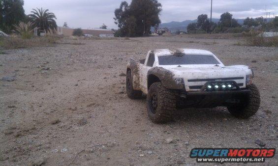 White remote control truck covered in mud, with four LED lights on the front bumper