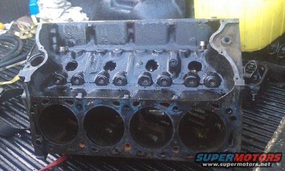 Black engine block with cylinder bores visible, sitting in a truck bed