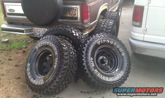 Brown Ford Bronco rear with spare tire and four off-road tires in foreground
