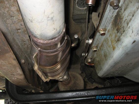 Underside view of a vehicle's exhaust system, showing a catalytic converter and pipe