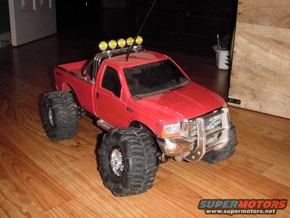 Red remote control monster truck with large tires and light bar on top