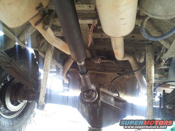 Undercarriage of a vehicle showing leaf springs, differential, driveshaft, and exhaust system