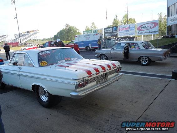 White drag car with red stripes on the trunk, rear view. License plate visible