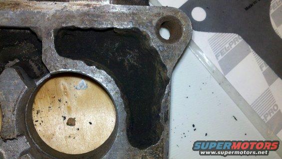 Engine part with carbon buildup and a gasket. Text 'FEL-PRO' is visible