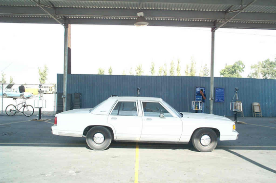 White sedan parked under a covered area. A bicycle is visible on the left