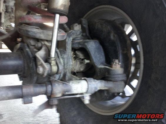 Close-up of front suspension and steering linkage with coil spring and shock absorber