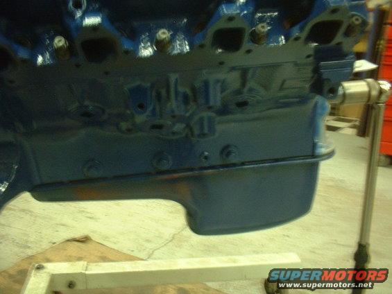 Blue painted engine block with intake manifold ports visible, mounted on an engine stand