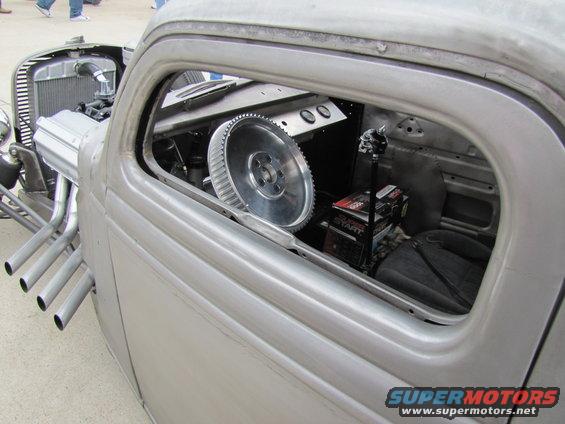 Hot rod interior with large metal steering wheel, shifter, and side exhaust pipes