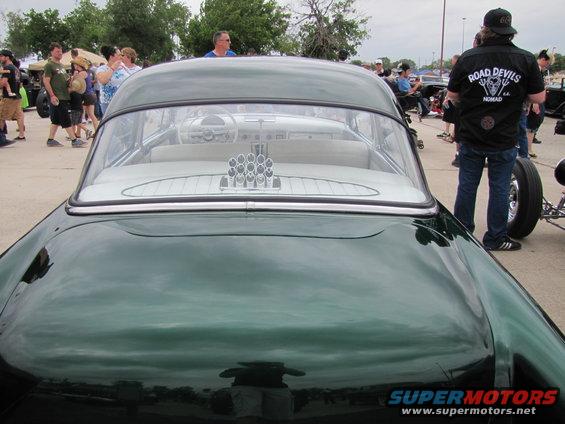 Green classic car interior with white upholstery and chrome accents visible through rear window