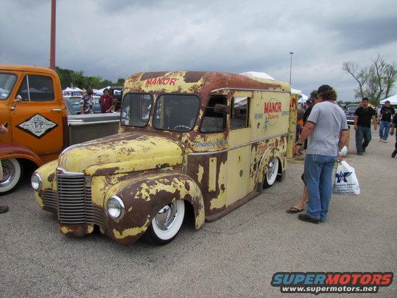 Rusted yellow ice cream truck with 'MANOR' text, low profile