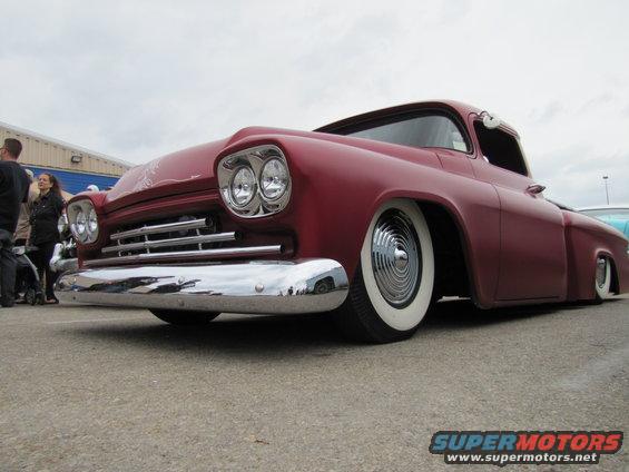 Red pickup truck front view, whitewall tires, chrome bumper, lowered suspension