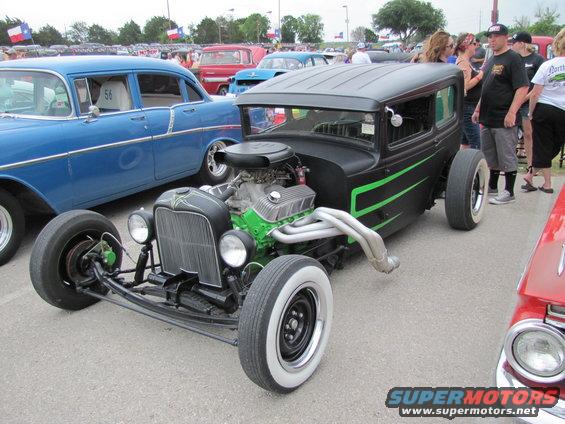 Black hot rod with green stripes and a big engine next to a blue classic car