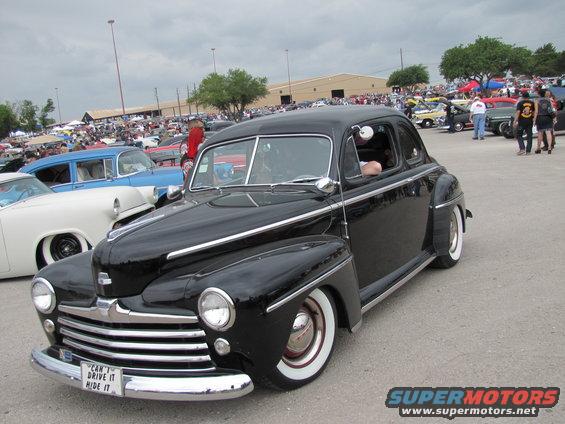 Black classic coupe with whitewall tires and a license plate that reads "CAN'T DRIVE IT HIDE IT"
