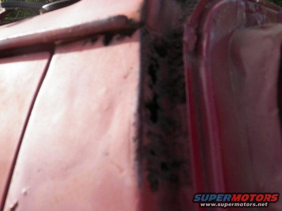 Red vehicle door frame showing rust damage
