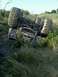1990 Ford Bronco - An overturned off-road vehicle rests on its side in a grassy field under a clear sky.