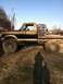 1990 Ford Bronco - This lifted flatbed truck, likely a 1979 Ford F-Series, is carrying a purple Jeep on its bed.