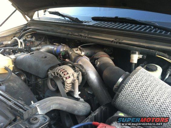 Engine bay with turbocharger, air filter, and alternator visible. Supermotors.net logo in lower right