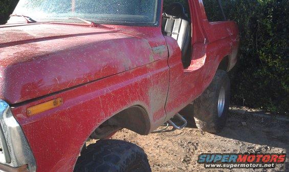 Red 1978 Ford Bronco with door open, parked on dirt