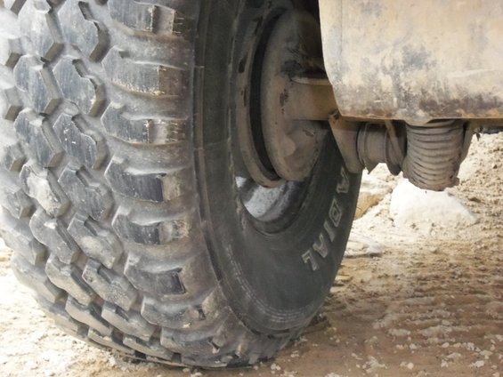 Close-up of a large off-road tire with 'RADIAL' visible on the sidewall, showing part of the suspension