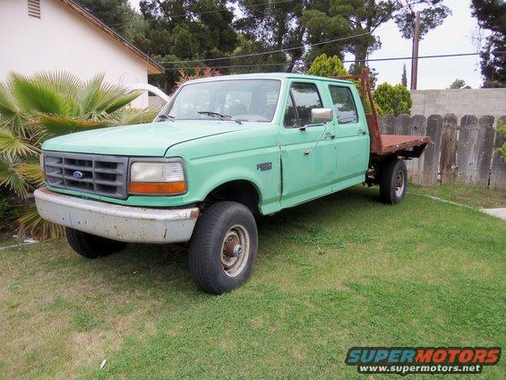 Green Ford F-Series crew cab truck with a flatbed parked on grass