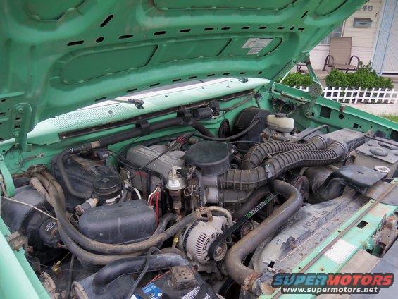 Green engine bay with V8 engine, air intake, alternator, and battery visible