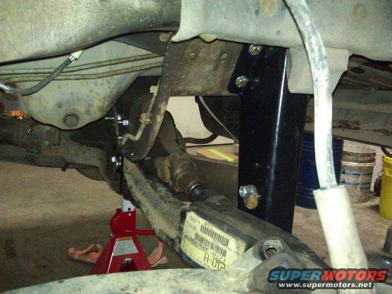 Close-up of truck's suspension with a jack stand underneath. Shows part of the axle and frame