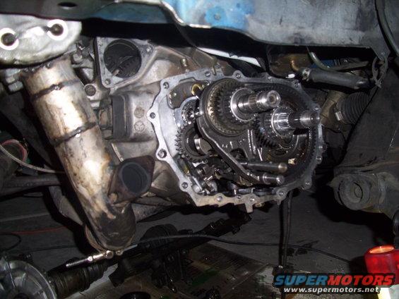 Close-up of exposed car transmission gears and exhaust pipe
