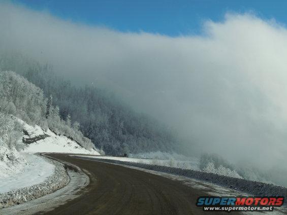 Winding road through a snowy mountain pass with fog
