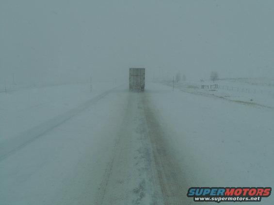 Truck trailer on a snow-covered road in a blizzard