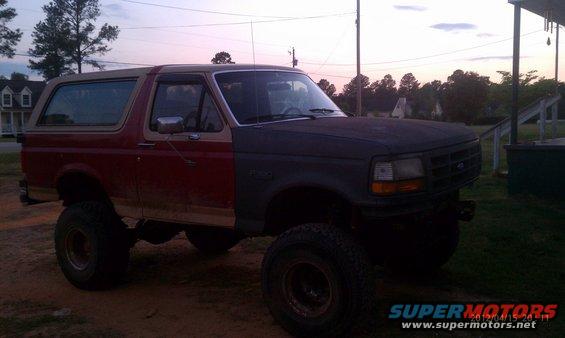 Ford Bronco with a red rear half and a dark gray front half, lifted on large tires