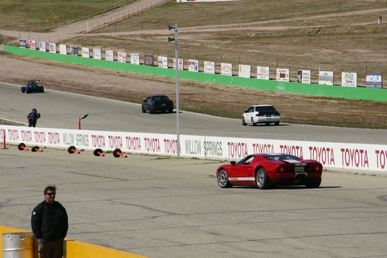 Red sports car with white stripes on a race track, rear view