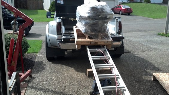 Engine on pallet loaded into pickup truck bed with ramp