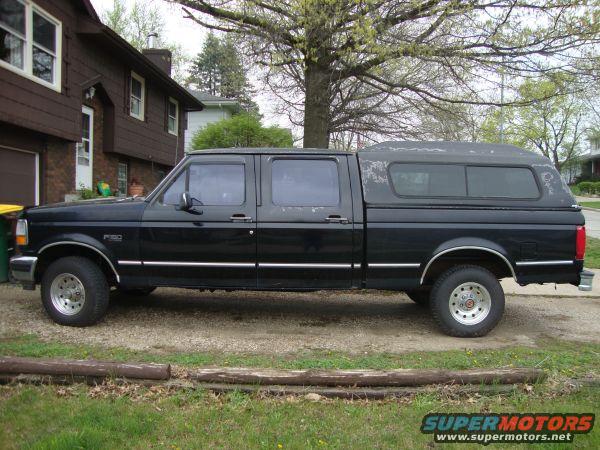 black crew cab pickup truck with a camper shell parked in front of a house