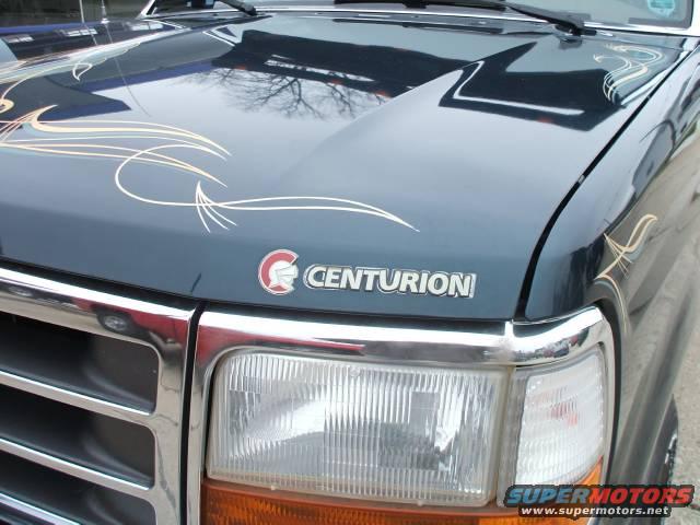 Dark blue truck hood with chrome grille, headlights, and pinstripe graphics. Centurion badge is visible
