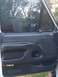 1993 Ford Bronco - The interior door panel of a vehicle shows storage compartments and window controls, with greenery visible outside.