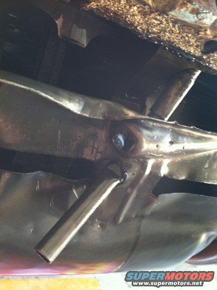 Underside view of a bent exhaust pipe and chassis components