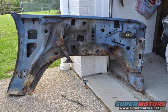 Rusted blue fender and inner wheel well structure with visible spring mechanism