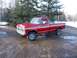 1978 Ford F-250 - A red pickup truck sits on a muddy road with trees and snow in the background.