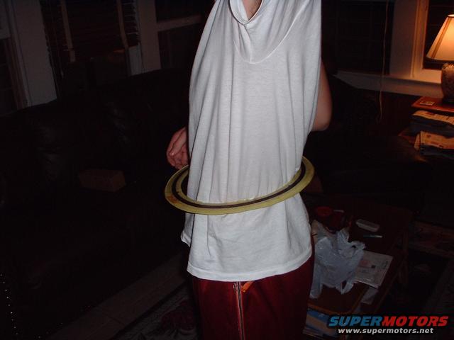 Person in white shirt and red pants with a hula hoop around their waist, indoors