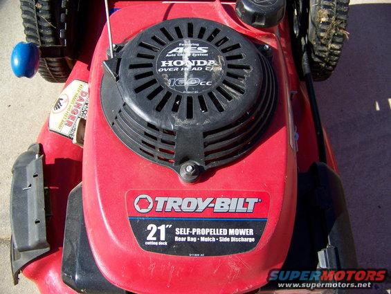 Red Troy-Bilt 21-inch self-propelled mower with Honda 160cc engine, close-up on deck and engine