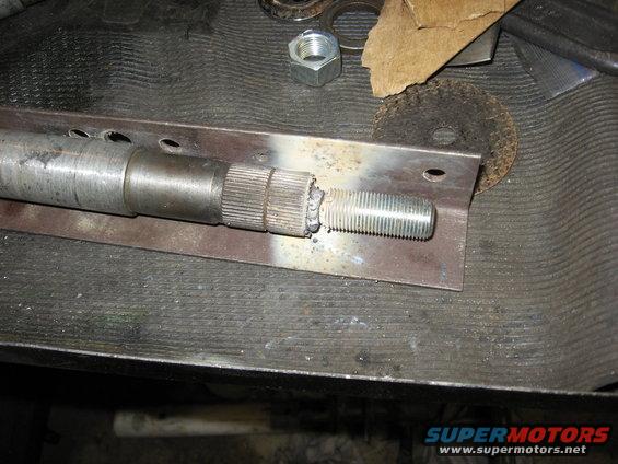 Metal shaft with splines and a welded threaded end, mounted on a metal plate