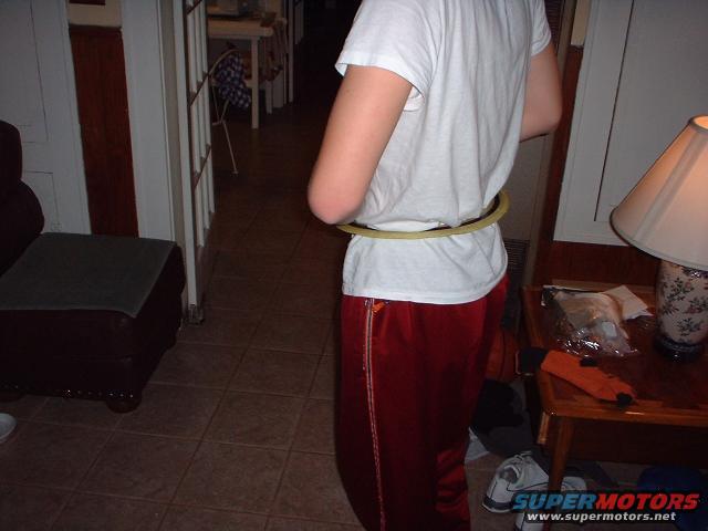 Person wearing red track pants and a white t-shirt, with a yellow hula hoop around their waist