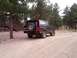 1994 Ford Bronco - This black 1994 Ford Bronco is seen from the rear, parked on a dirt road surrounded by trees.