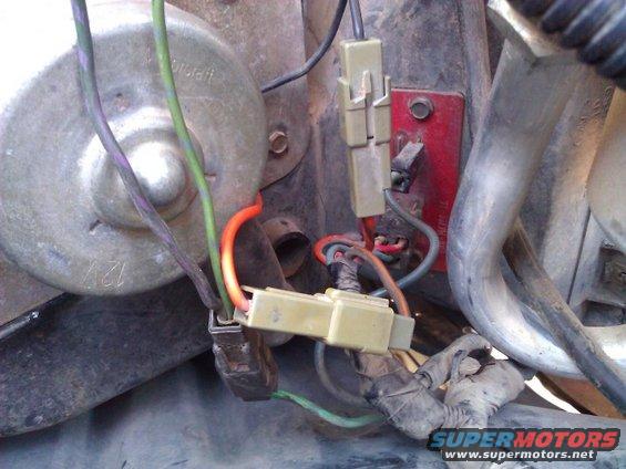 Close-up of vehicle wiring, connectors, and a motor labeled 12V